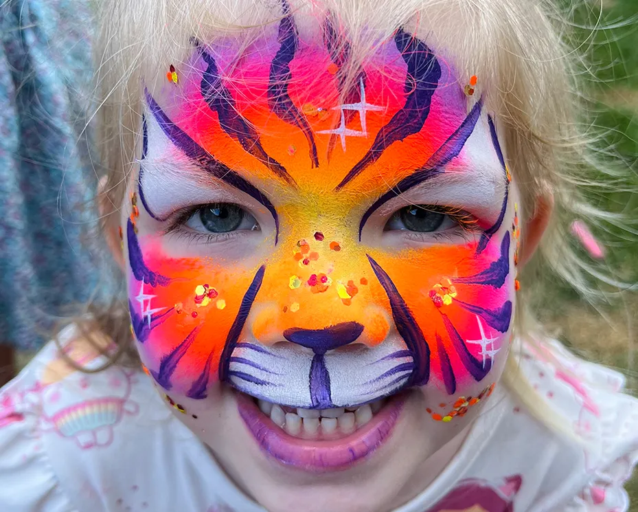 A kid proudly displaying an amazing facepaint artwork